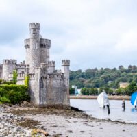 Sailboats pass an ancient stone church in Cork, Ireland